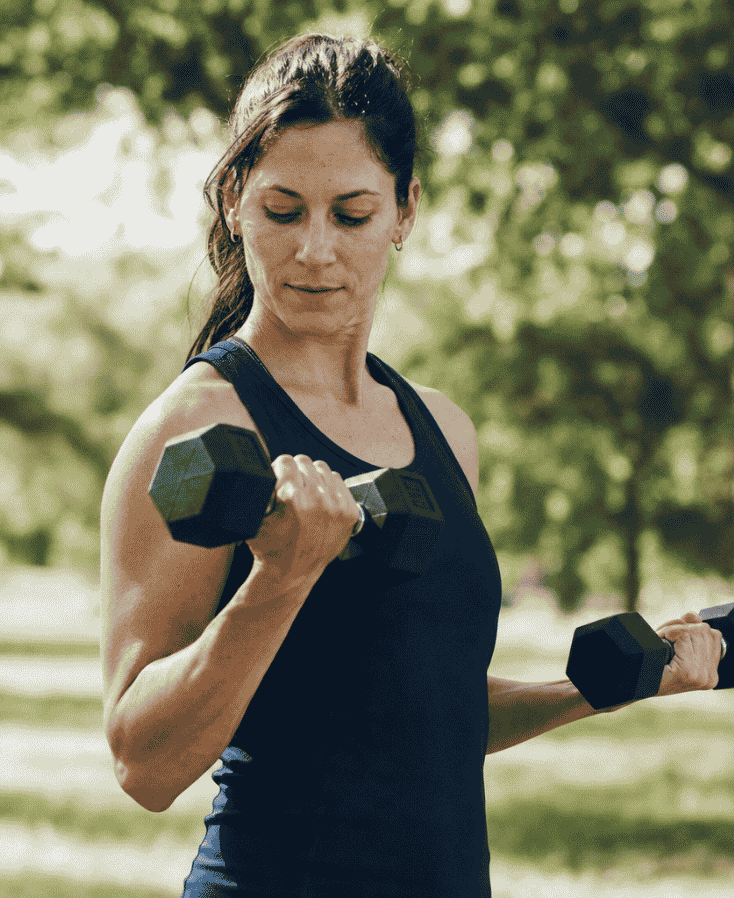 woman lifting dumbbells outdoors
